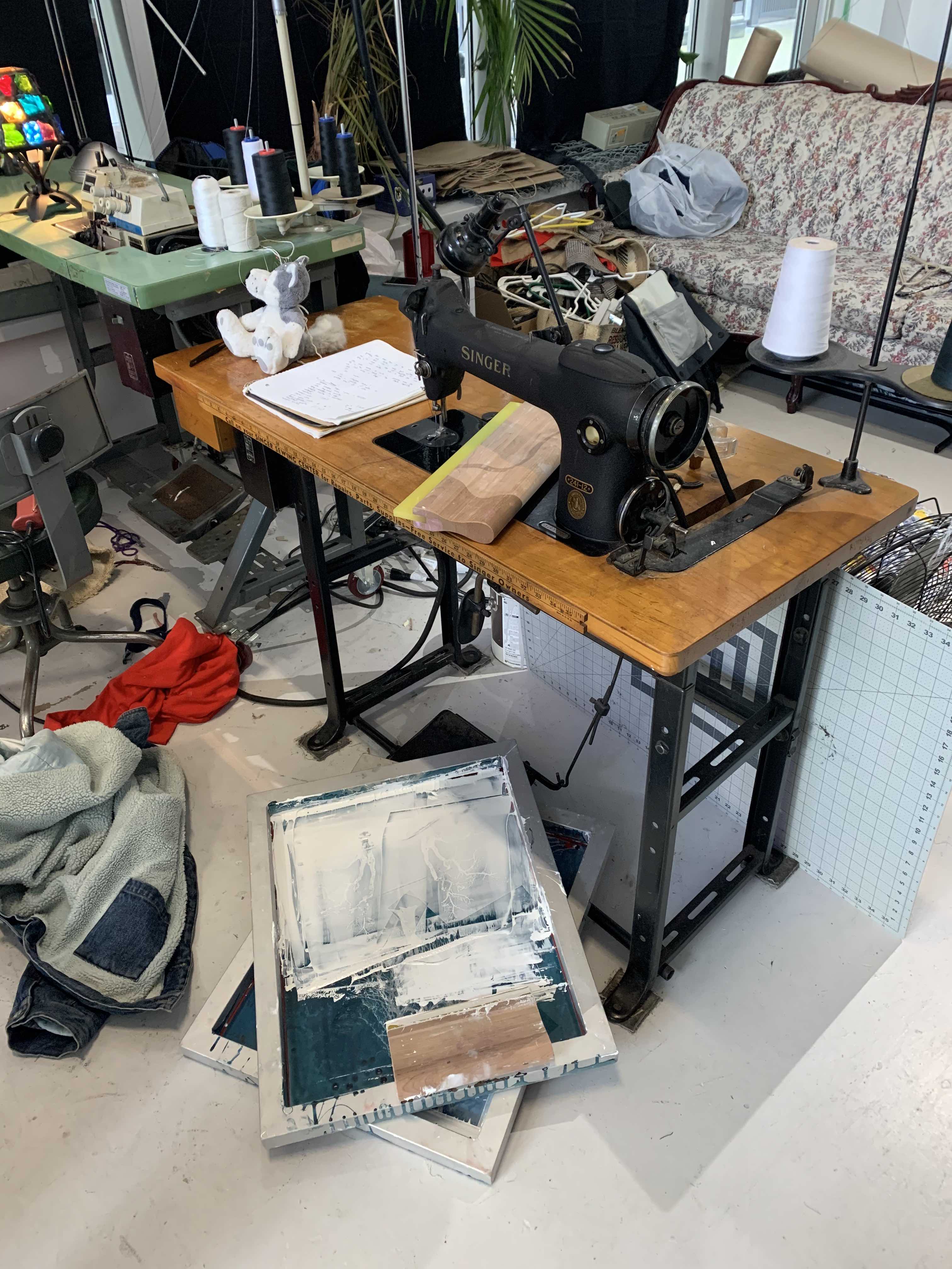 mess scattered on floor including screen printing materials and a sewing machine